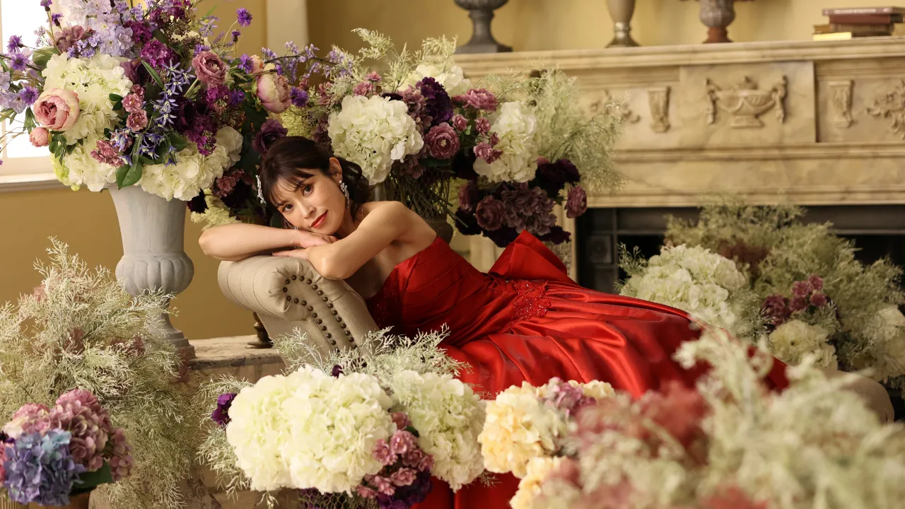 真紅のドレスを着た花嫁がフラワーセットの中で微笑む