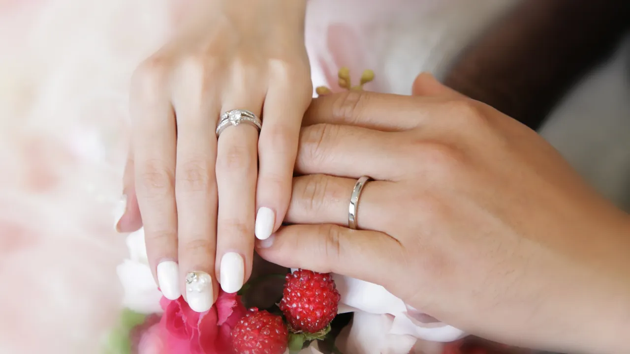 結婚指輪をつけたカップルの手元と幸せな雰囲気のイメージ