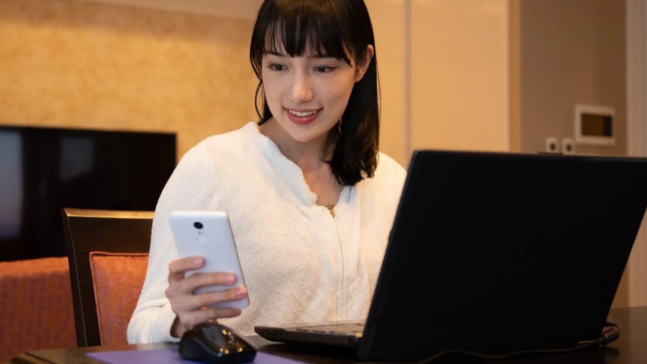 パソコンとスマホで家計管理をする女性