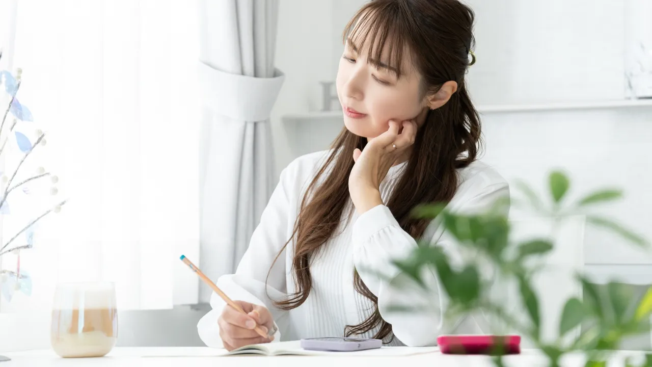 婚活中の女性が家計簿を見ながら将来の生活を考えている様子