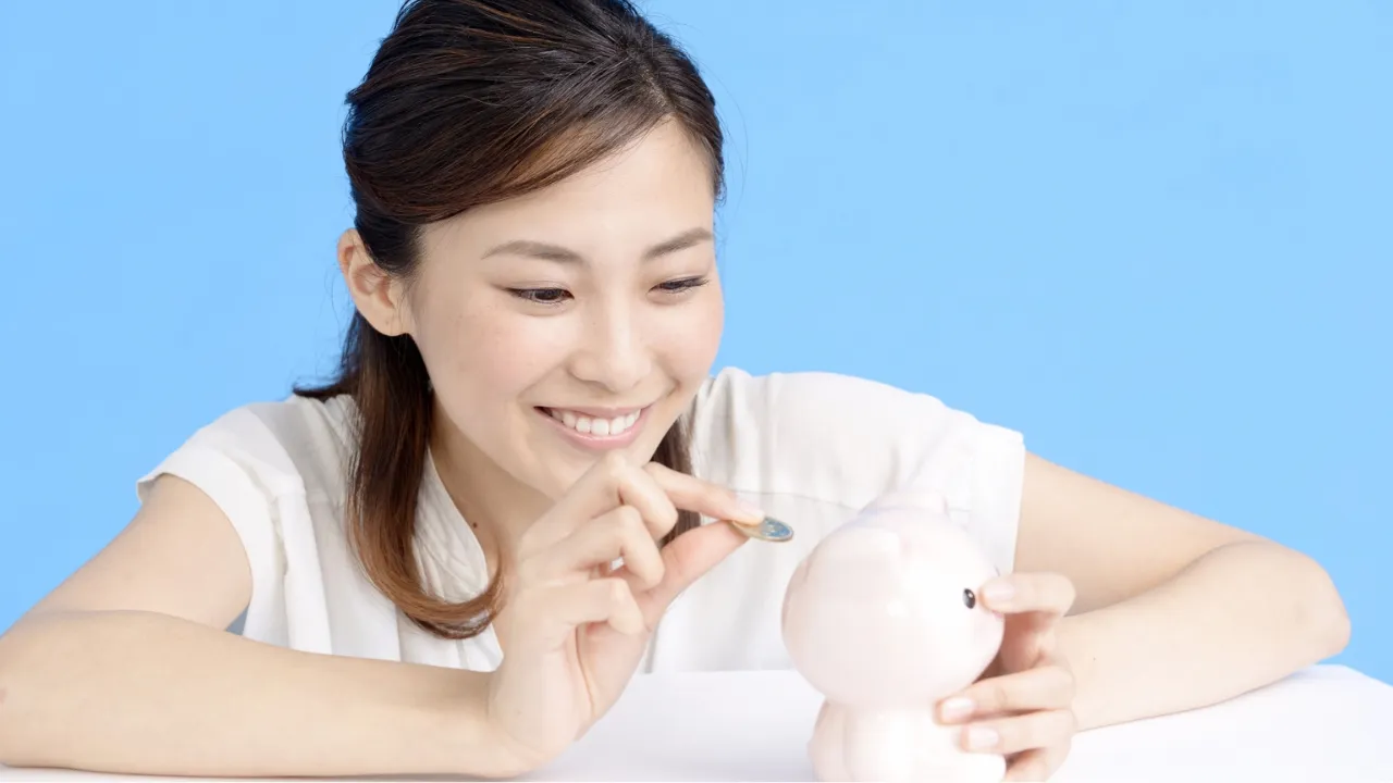 貯金箱にコインを入れて節約習慣を楽しむ女性