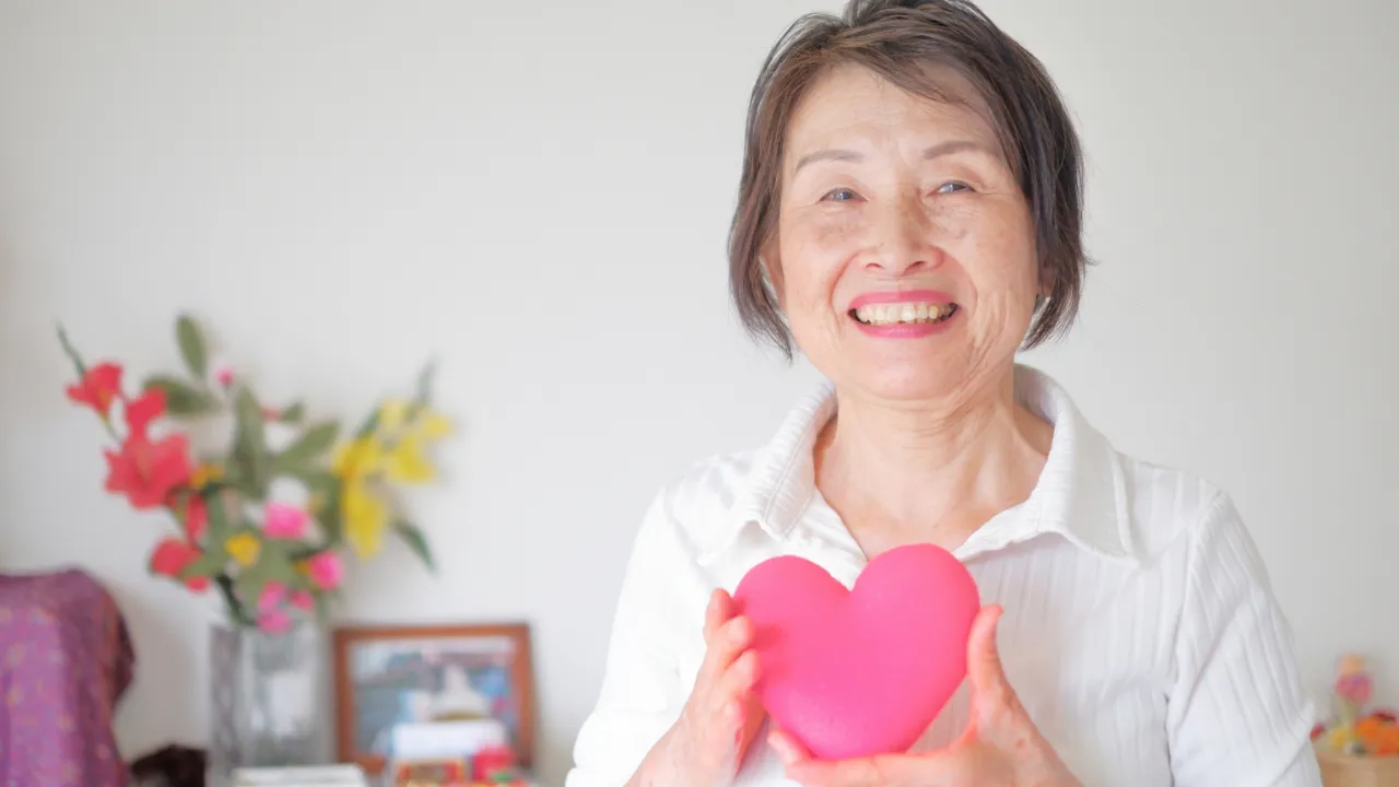 ハートを持って笑顔を見せる年配の女性
