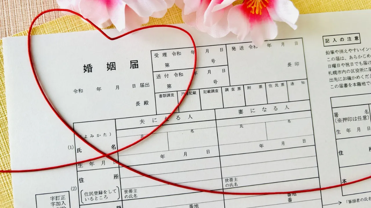 ハート型の赤い紐で飾られた婚姻届と梅の花