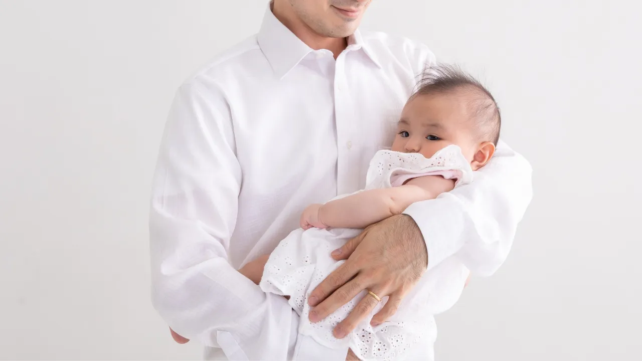 赤ちゃんを抱くアラフィフ男性のイメージ写真