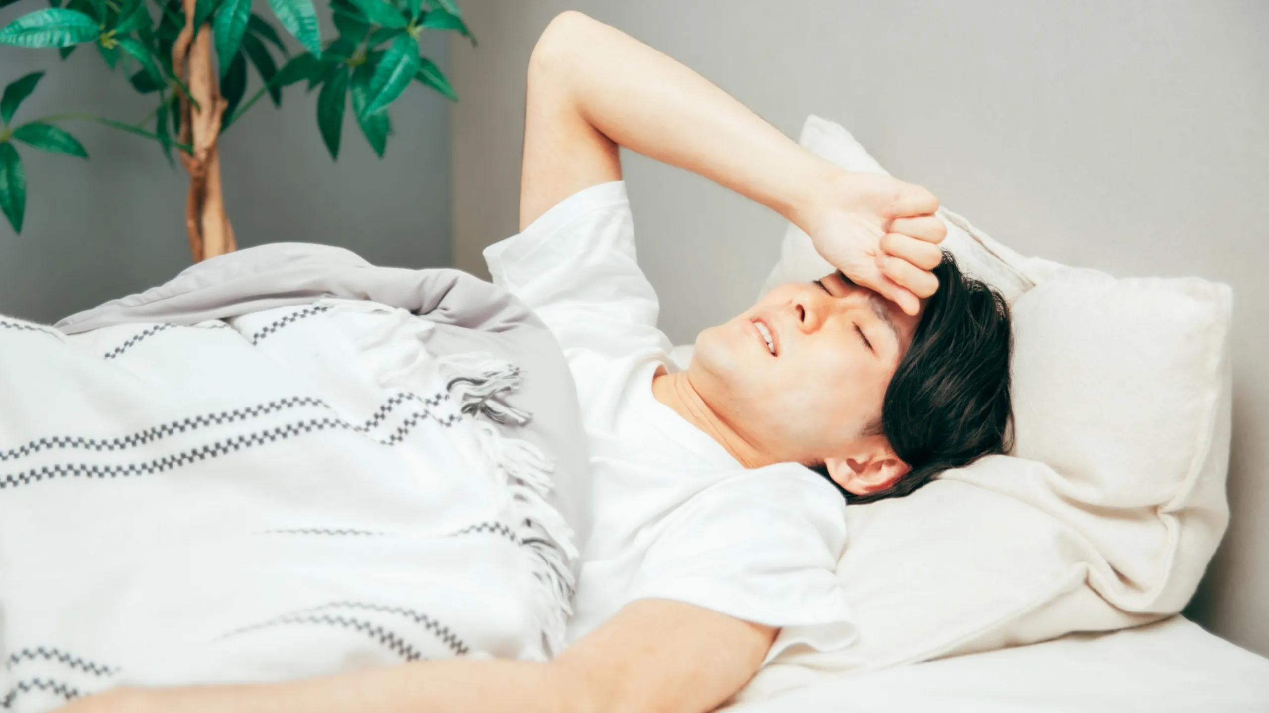 体調不良で横になる男性のイメージ