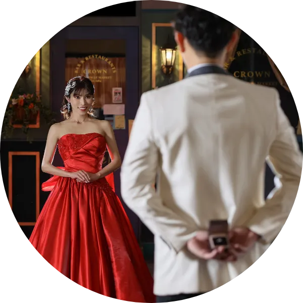 男性が指輪を持って女性にプロポーズしようとしている場面。赤いドレスを着た女性が嬉しそうに微笑んでいる様子