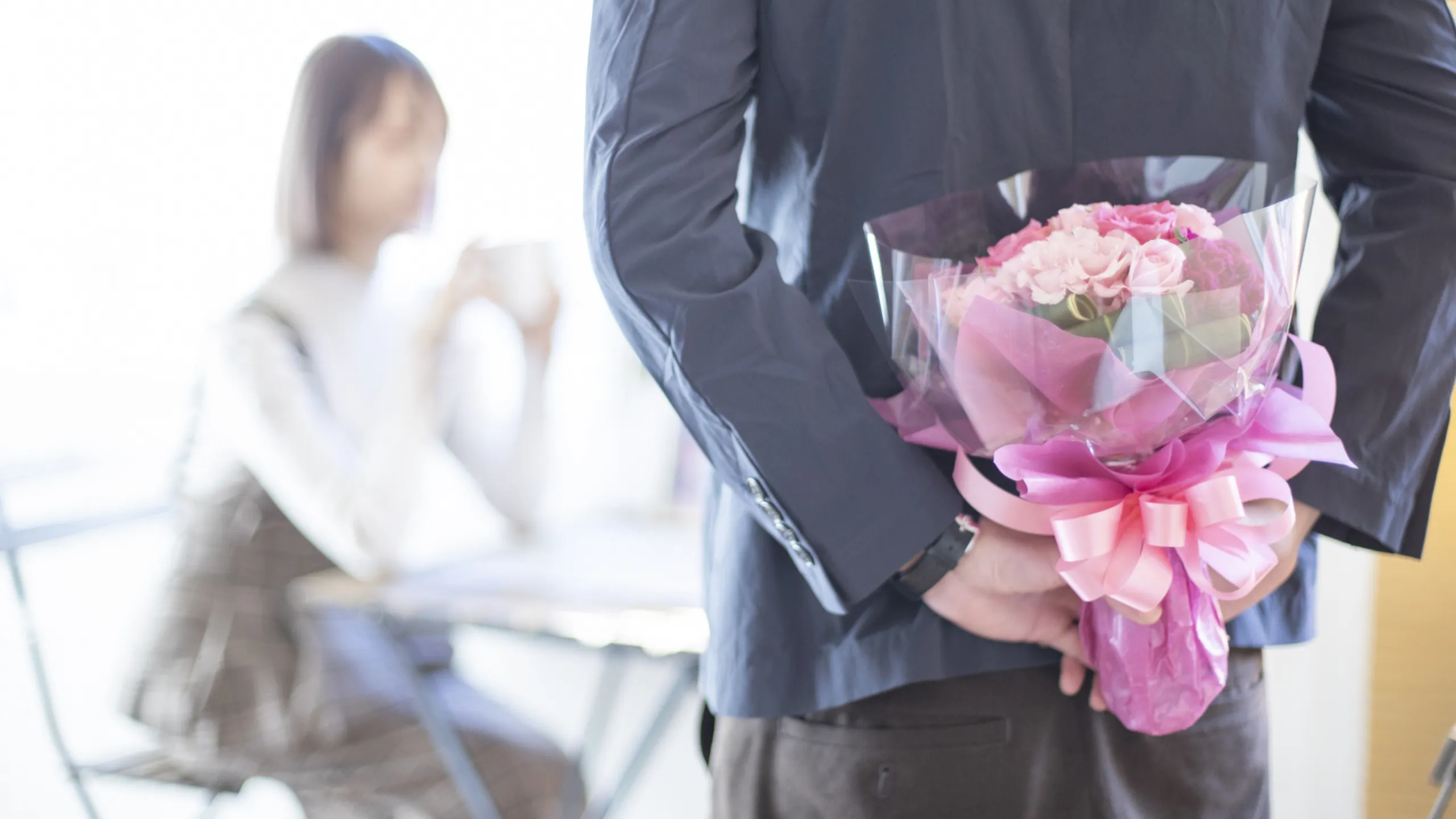 カフェで女性に花束をサプライズする男性