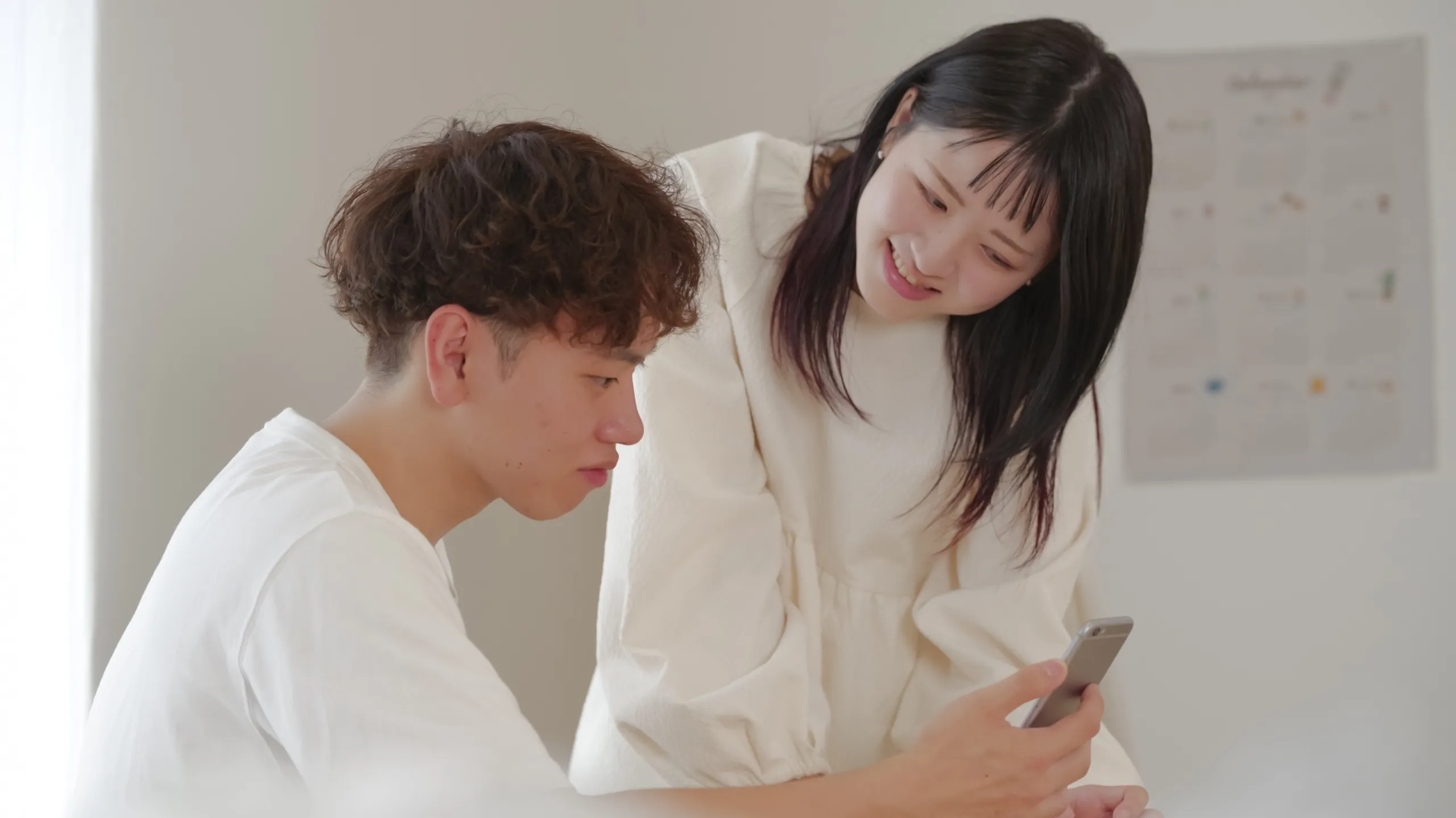 夫婦がスマートフォンで教育資金の貯め方を相談しているイメージ