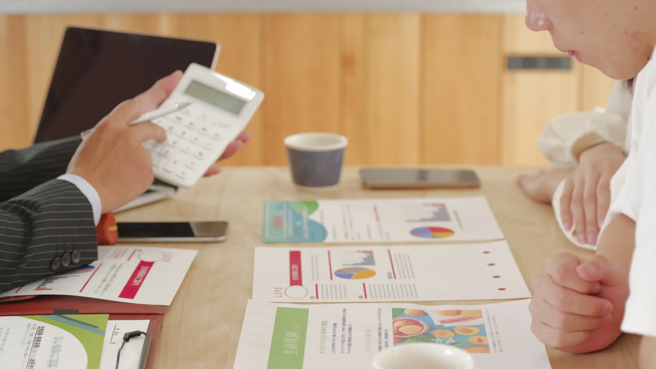 ファイナンシャルプランナーが電卓を使いながら教育資金の資料を説明している様子