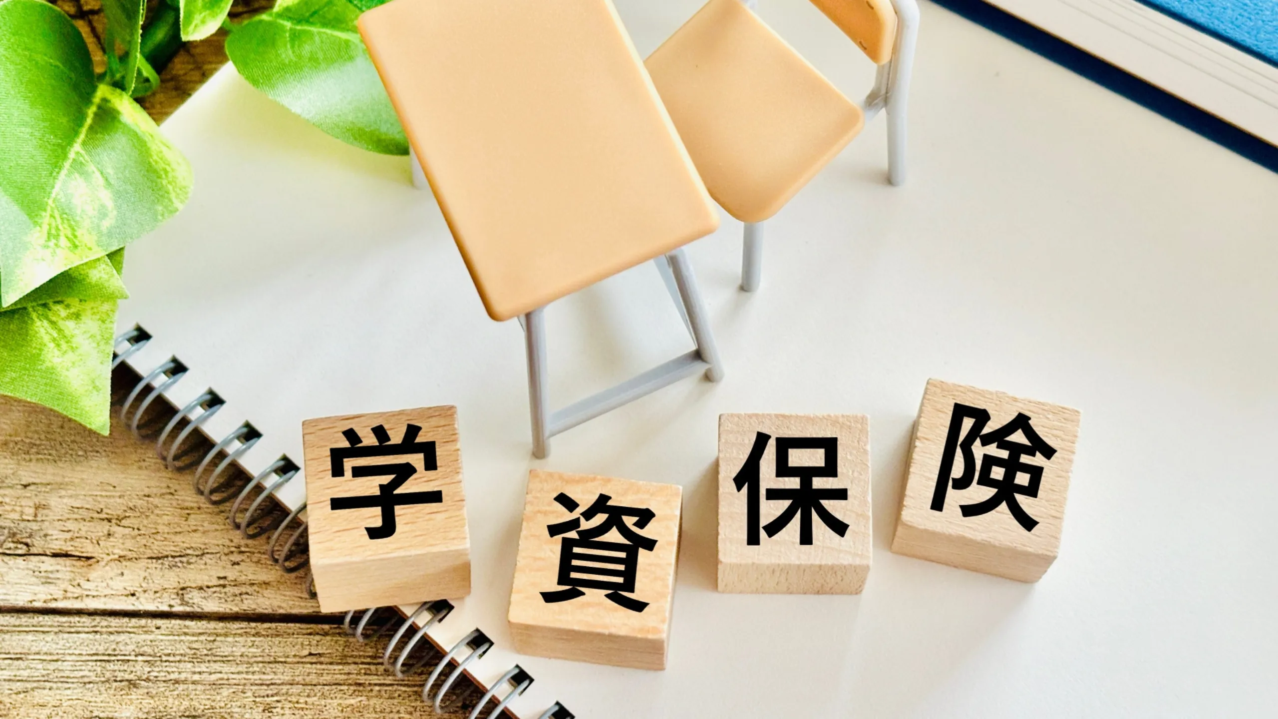 学資保険をイメージしたノートと机の上のブロックの写真